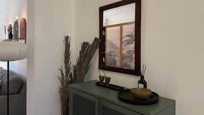 Une pièce au décor minimaliste, avec un meuble aux teintes sombres, une œuvre d’art encadrée et une petite table sur laquelle se trouvent un bol et une bougie.