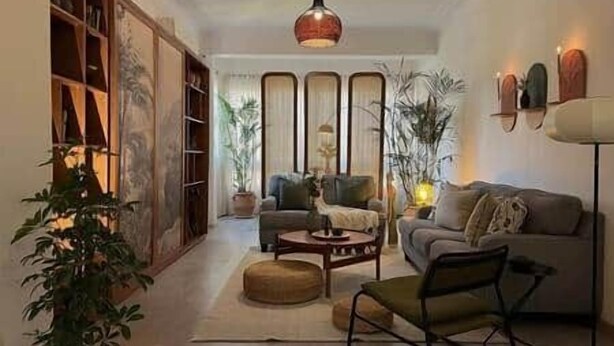 Un salon comprenant un canapé, des fauteuils, une table basse et une bibliothèque.