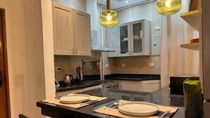 Une cuisine moderne avec un plan de travail noir, deux assiettes blanches et un couteau.