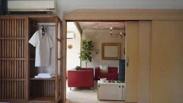 A room with a bed, a wardrobe, and a red sofa.