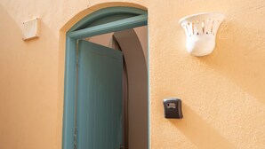 Uma porta azul-turquesa com um buraco de fechadura, uma luminária fixada na parede e um dispositivo de segurança.
