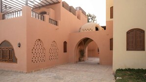Pátio com arcos e galeria coberta, rodeado por edifícios com elementos arquitetônicos tradicionais.