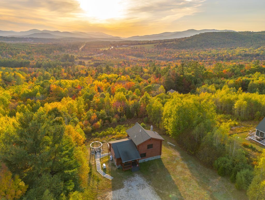 A cabin surrounded by dense forest with a clear view of the surrounding landscape.