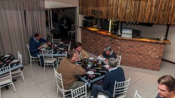 A group of people dining at a restaurant with a brick counter and white chairs.
