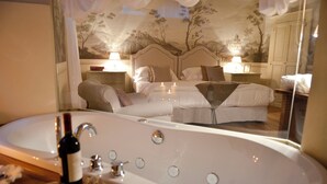 A hotel room with a large bathtub, a bed with two pillows, and a nightstand with a lamp. - La Corte Di Ambra Historical House - Historical Center of Cortona (Cortona)