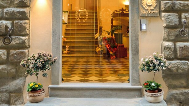 A stone archway entrance with a checkered floor leading inside, two potted plants, and a chandelier. - La Corte Di Ambra Historical House - Historical Center of Cortona (Cortona)