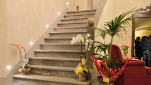 A staircase with a checkered floor, a red armchair, and various potted plants. - La Corte Di Ambra Historical House - Historical Center of Cortona (Cortona)