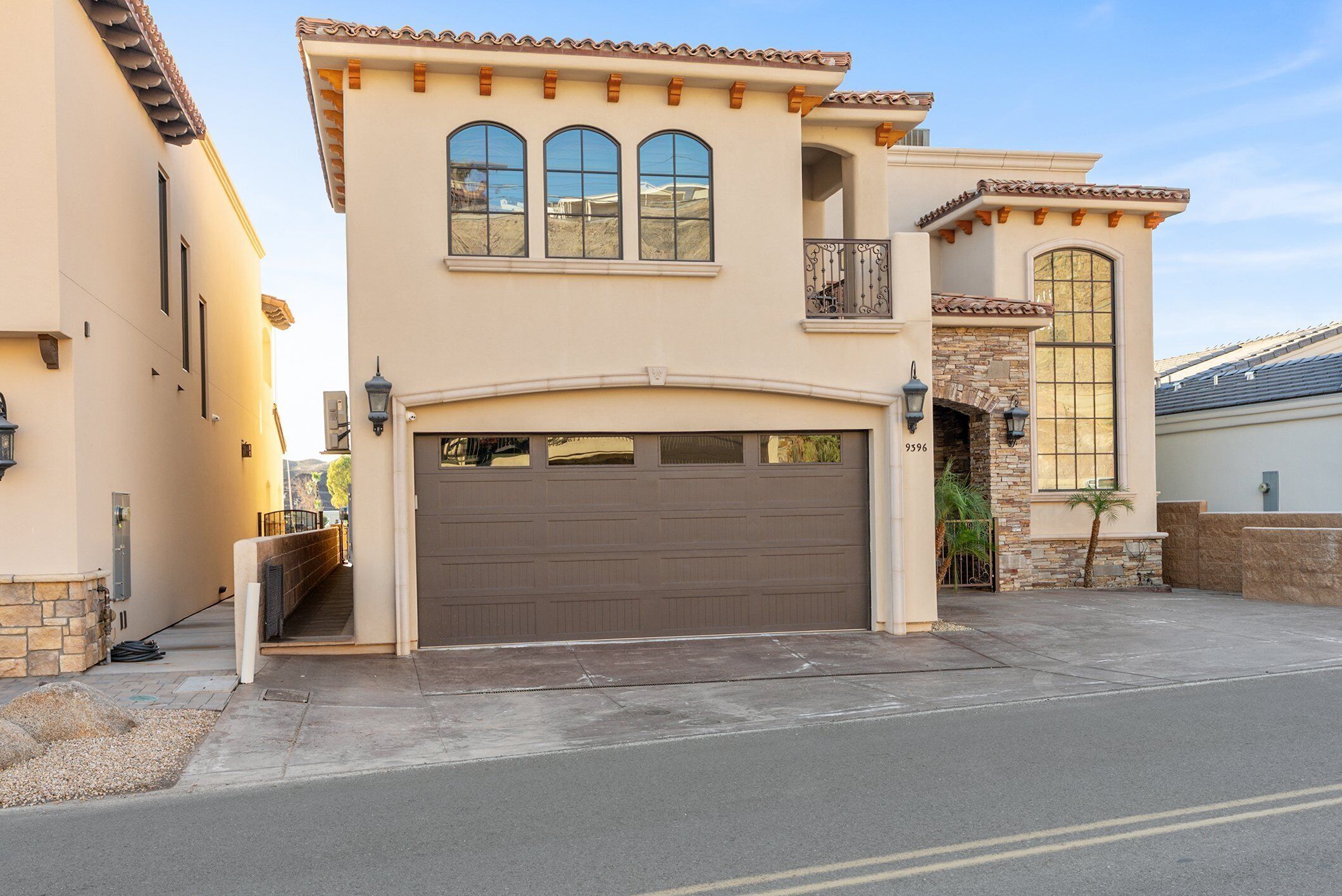 Une maison à deux étages avec un garage, un balcon et une grande fenêtre en arc de cercle.