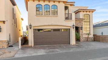Une maison à deux étages avec un garage, un balcon et une grande fenêtre en arc de cercle.