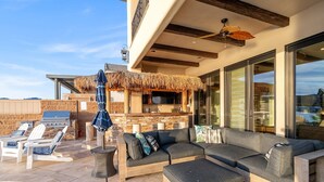A modern outdoor living area with a large sectional sofa, a pool, and a barbecue grill. - Splash Landing |  Riverfront Estate with Infinity Pool, Guest House & Private Docks (Parker)