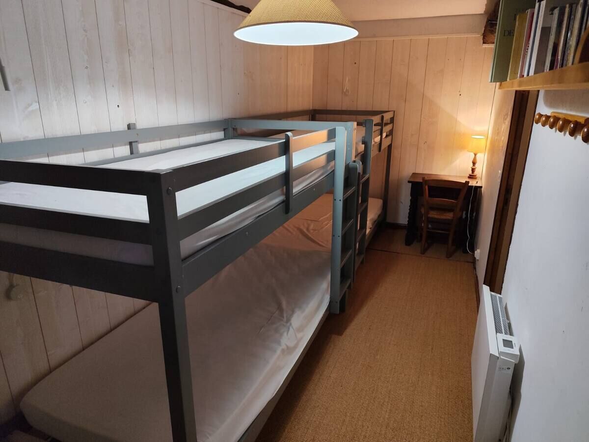 Habitación con literas, paredes de madera y una pequeña mesa con lámpara.