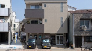 A multi-story residential building with a flat facade, a ground-level entrance, and a small balcony on the second floor. - Maison Raffine (Osaka)