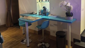 Een compacte, moderne werkruimte met een blauwe bureau, twee stoelen, een koffieapparaat en een klein plankje met mokken.