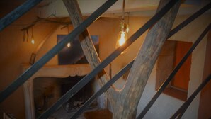 A rustic interior with a wooden staircase, a hanging light bulb, and a fireplace. - Gite for two people Le frêne (Rosay)