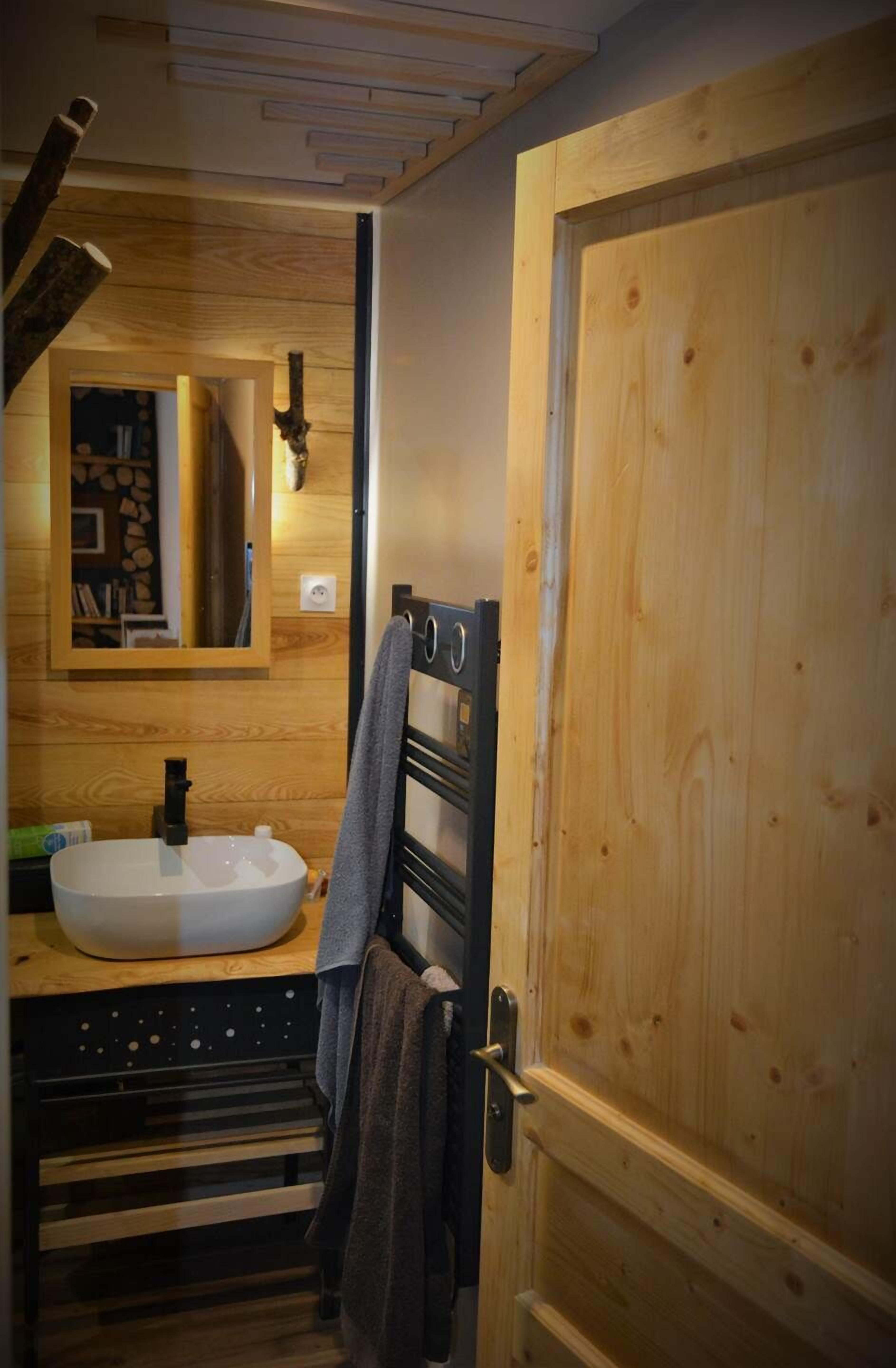 A wooden bathroom with a sink, mirror, and towel rack.