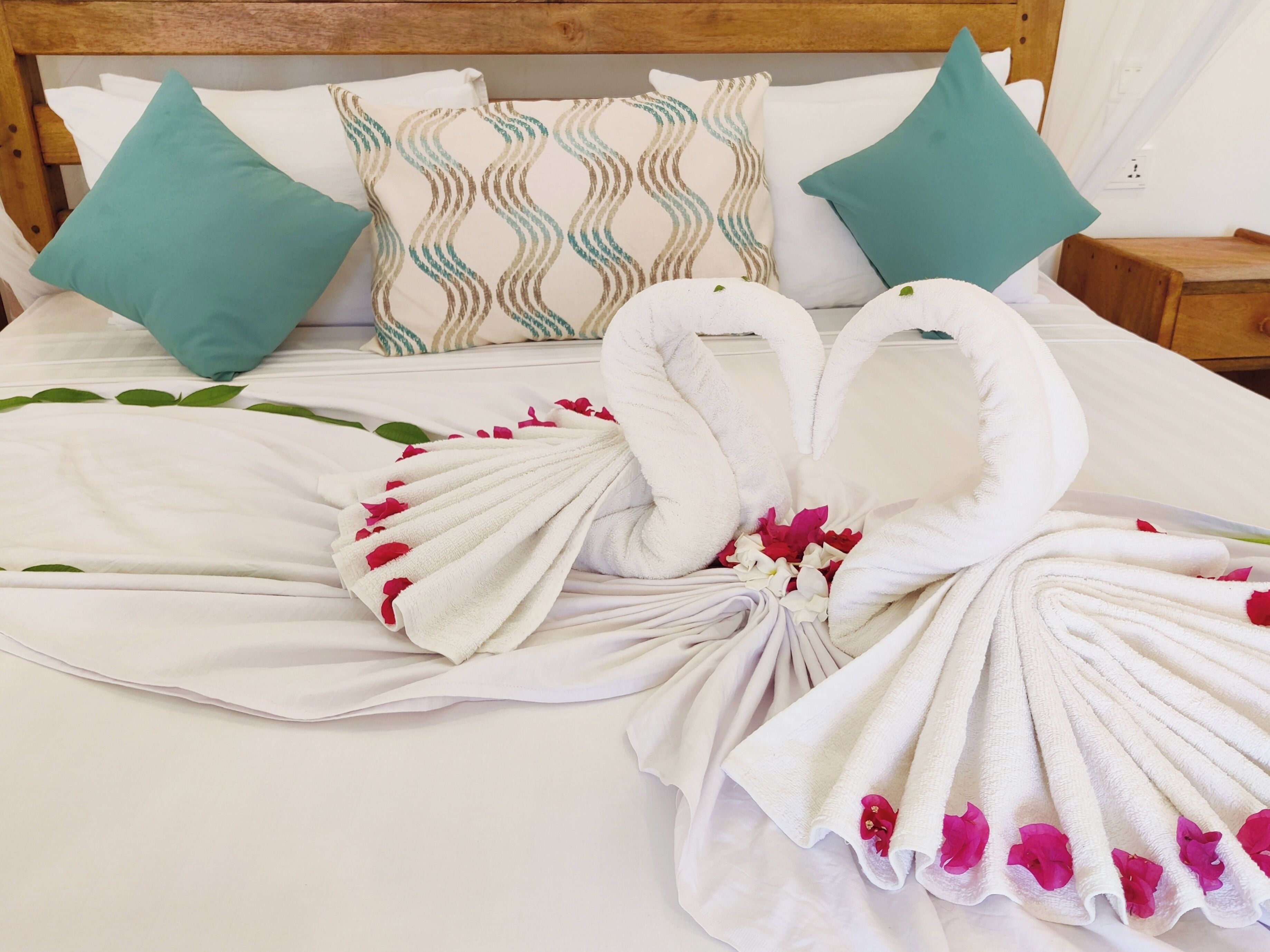 Una cama bien hecha con una escultura de toallas y almohadones decorativos.