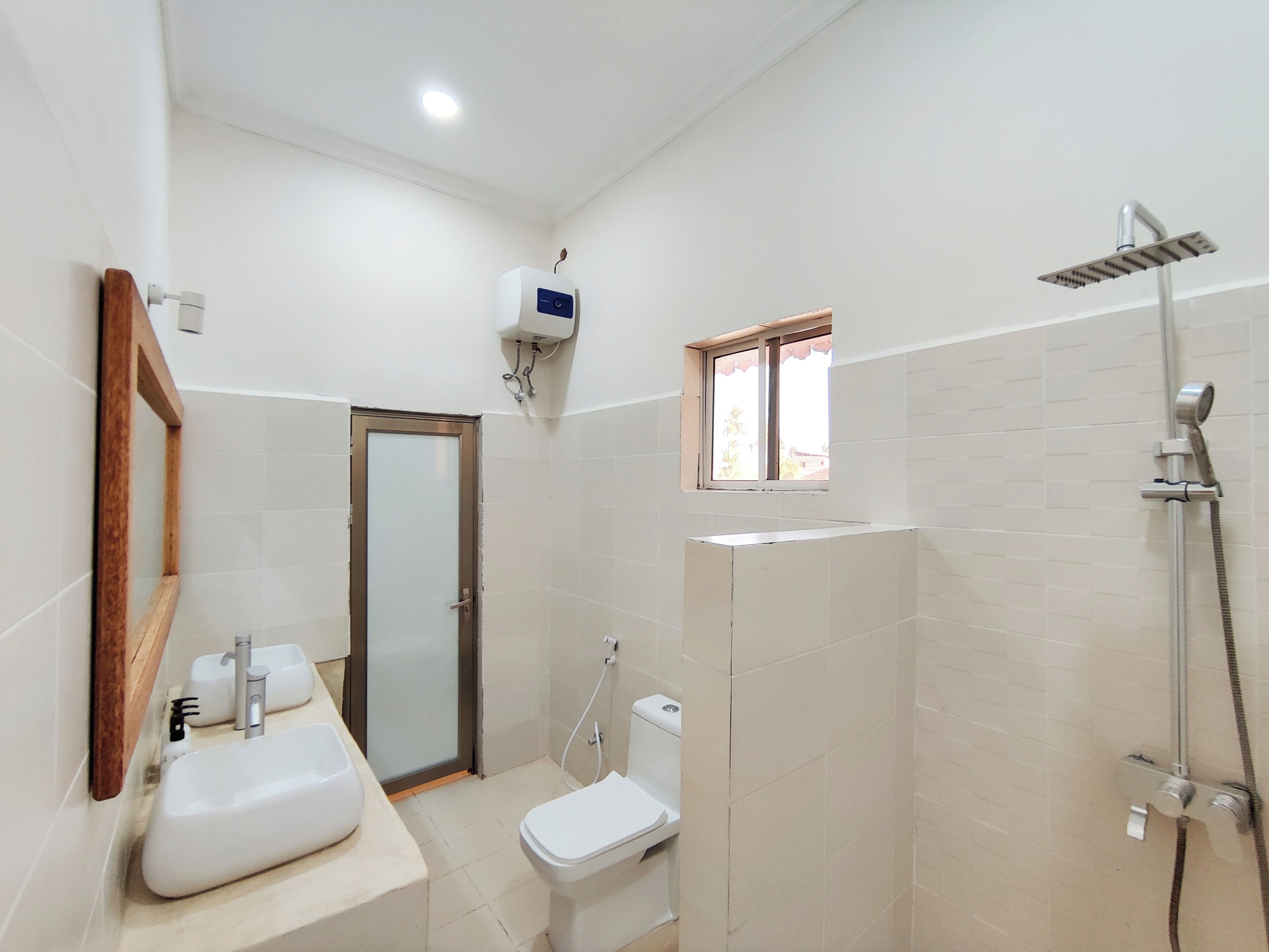 Un baño con ducha, inodoro, lavamanos y ventana.