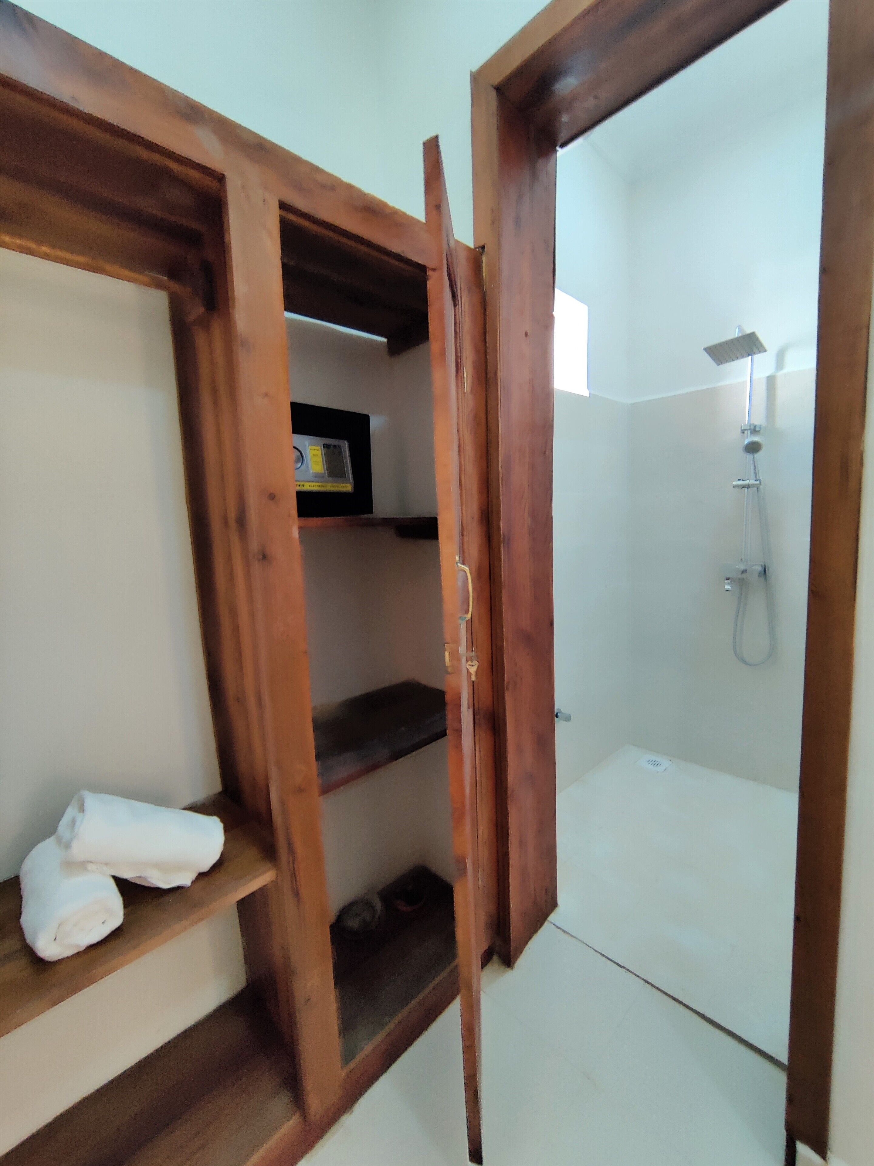 Porta in legno che conduce a un angolo doccia con soffione a mano e pannello di controllo a parete.