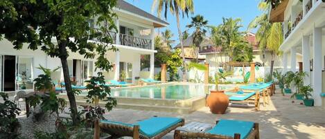 Un resort con piscina, sillas de descanso y palmeras.