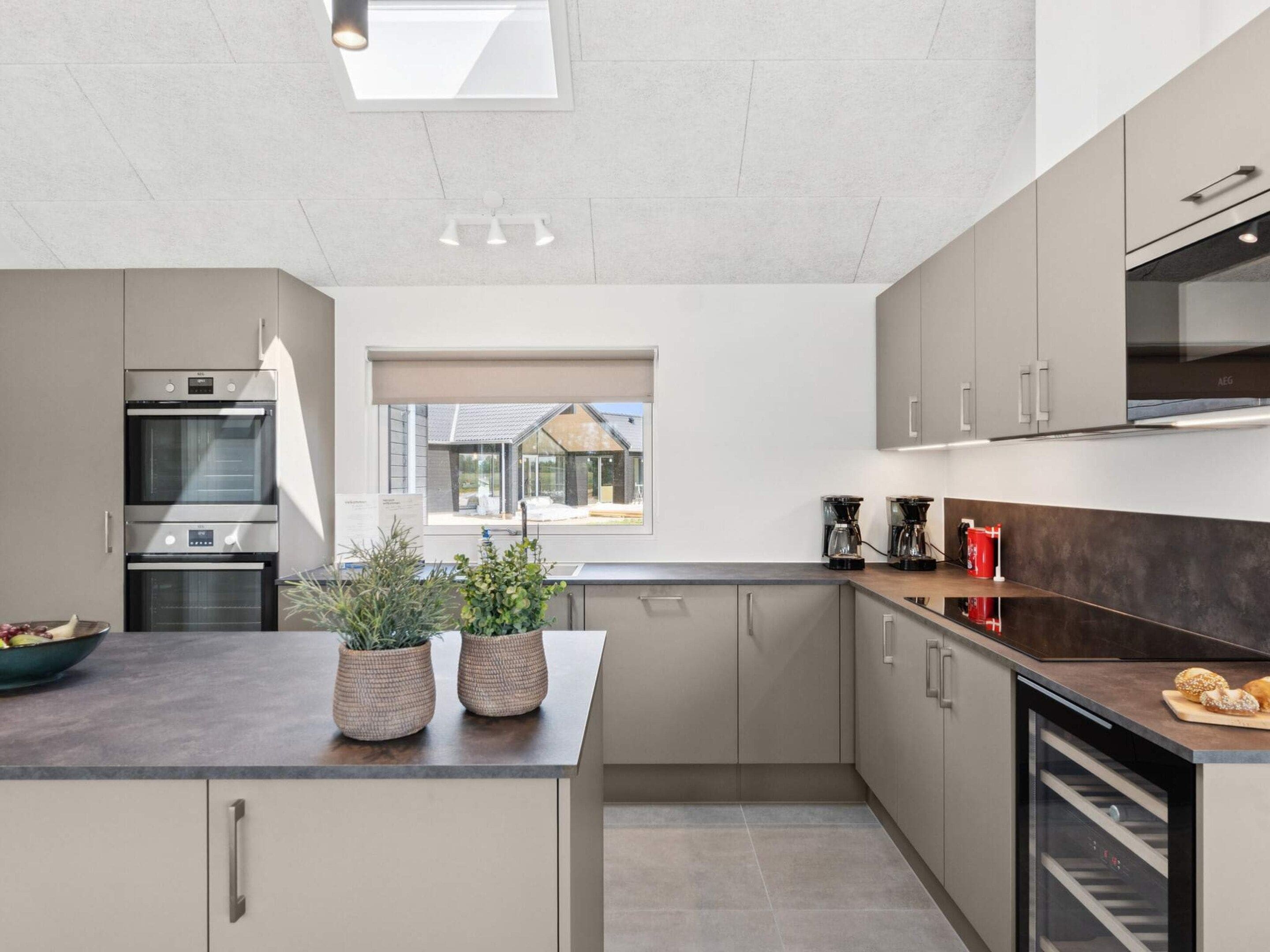 A modern kitchen with built-in appliances, a large window, and a view of the outside.