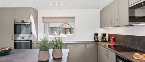 A modern kitchen with built-in appliances, a large window, and a view of the outside.