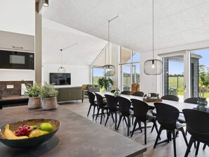 A modern kitchen with a large island, dining area with chairs, and a view of the outdoors. - 5 Star Holiday Home in Bogense (Bogense)