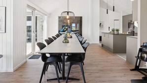 Zona pranzo moderna con un tavolo lungo, sedie nere e un lampadario particolare.
