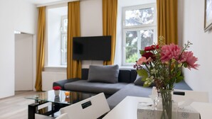 Una sala de estar moderna con un sofá, una mesa de centro de vidrio y un jarrón de flores.