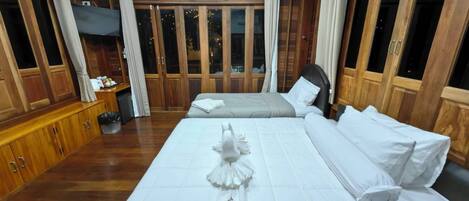 A hotel room with a large bed, wooden paneling, and a view through the windows.