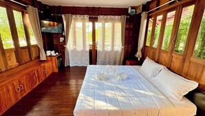 Een houten kamer met een bed, gordijnen, een televisie en een ventilator.