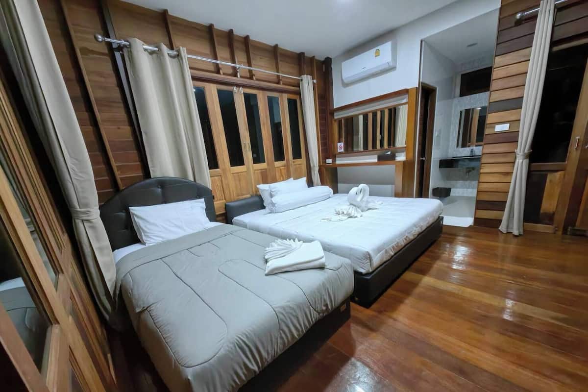 Habitación de hotel con dos camas, paneles de madera, armario empotrado y aire acondicionado.