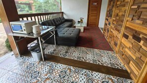 Een moderne kamer met een zwarte leren bank, een tafeltje met een magnetron, en een vloer met patroon.