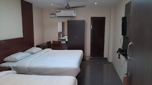 A hotel room with two beds, a desk, a wardrobe, an air conditioning unit, a television, and a ceiling fan. - Selvam Residency (Thoothukudi)