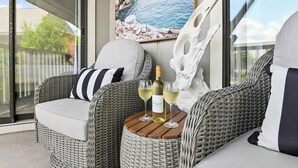A wicker sofa with a cushion, a bottle of wine, and two glasses on a wooden table. - The Vineyard on 30A  All NEW rental in Seagrove (Santa Rosa Beach)