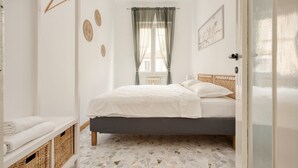 A bedroom with a bed, a window with sheer curtains, a radiator, and a wall-mounted picture. - Hostmate - Milano- Corso Garibaldi - Brera (Milano)