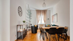 A modern dining area with a wooden table, black chairs, a white radiator, and a window with sheer curtains. - Hostmate - Milano- Corso Garibaldi - Brera (Milano)