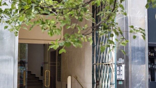 A modern building entrance with a glass door, metal railings, and a staircase leading inside. - Hostmate - Milano- Corso Garibaldi - Brera (Milano)