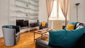A modern living room with a sofa, a coffee table, a TV, and a bookshelf. - Hostmate - Milano- Corso Garibaldi - Brera (Milano)
