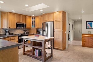 Una cocina moderna con armarios de madera, electrodomésticos de acero inoxidable y una isla central.