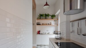 A modern kitchen with white brick walls, a hexagonal patterned floor, a built-in stove, and a hanging light fixture. - THE BREAK - PIAZZA DI SPAGNA MAISON DELUXE TERRACE (Roma)