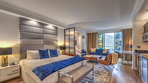 Une chambre d’hôtel moderne dotée d’un grand lit, d’un canapé, d’un coin repas et offrant une vue sur la ville.