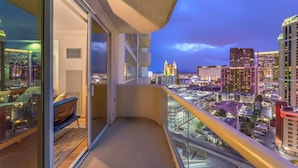 Un balcon offrant une vue sur la ville au crépuscule, avec des bâtiments modernes et un ciel dégagé.