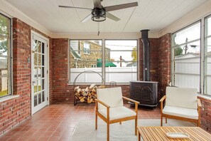 Ein Wintergarten mit Backsteinwänden, Kamin, zwei Stühlen und einem Tisch.