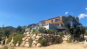 Een modern huis met een stenen fundering, grote ramen en een plat dak.