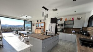 Een moderne keuken met een groot eiland, inbouwapparatuur en uitzicht op de omgeving.
