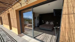 Een moderne slaapkamer met een groot bed, een glazen deur naar een balkon en uitzicht op de bergen.
