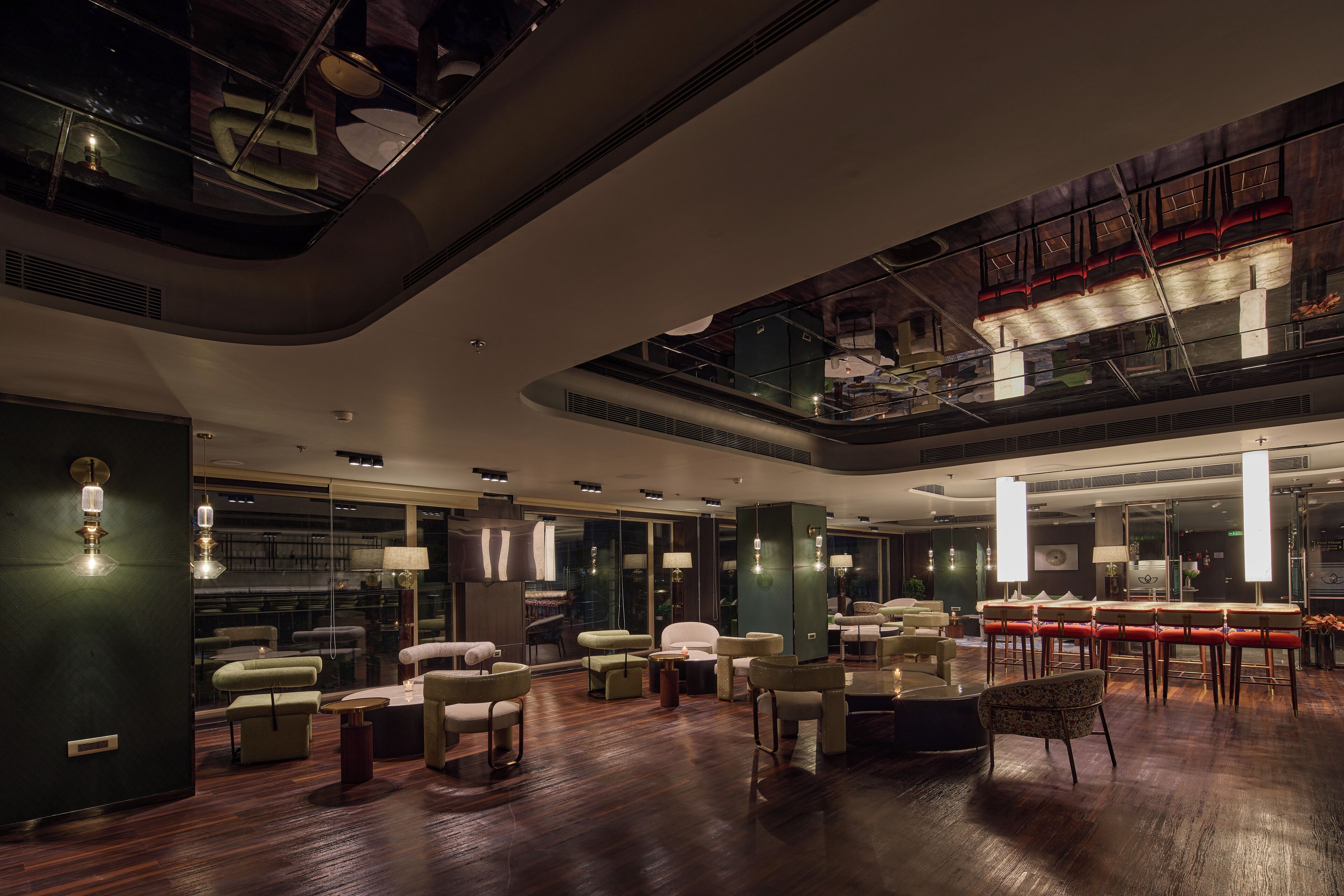 A spacious lobby with a high ceiling, modern furniture, and a glass railing overlooking the lower level.