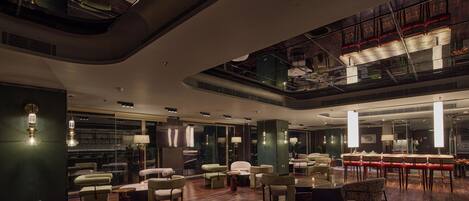 A spacious lobby with a high ceiling, modern furniture, and a glass railing overlooking the lower level.