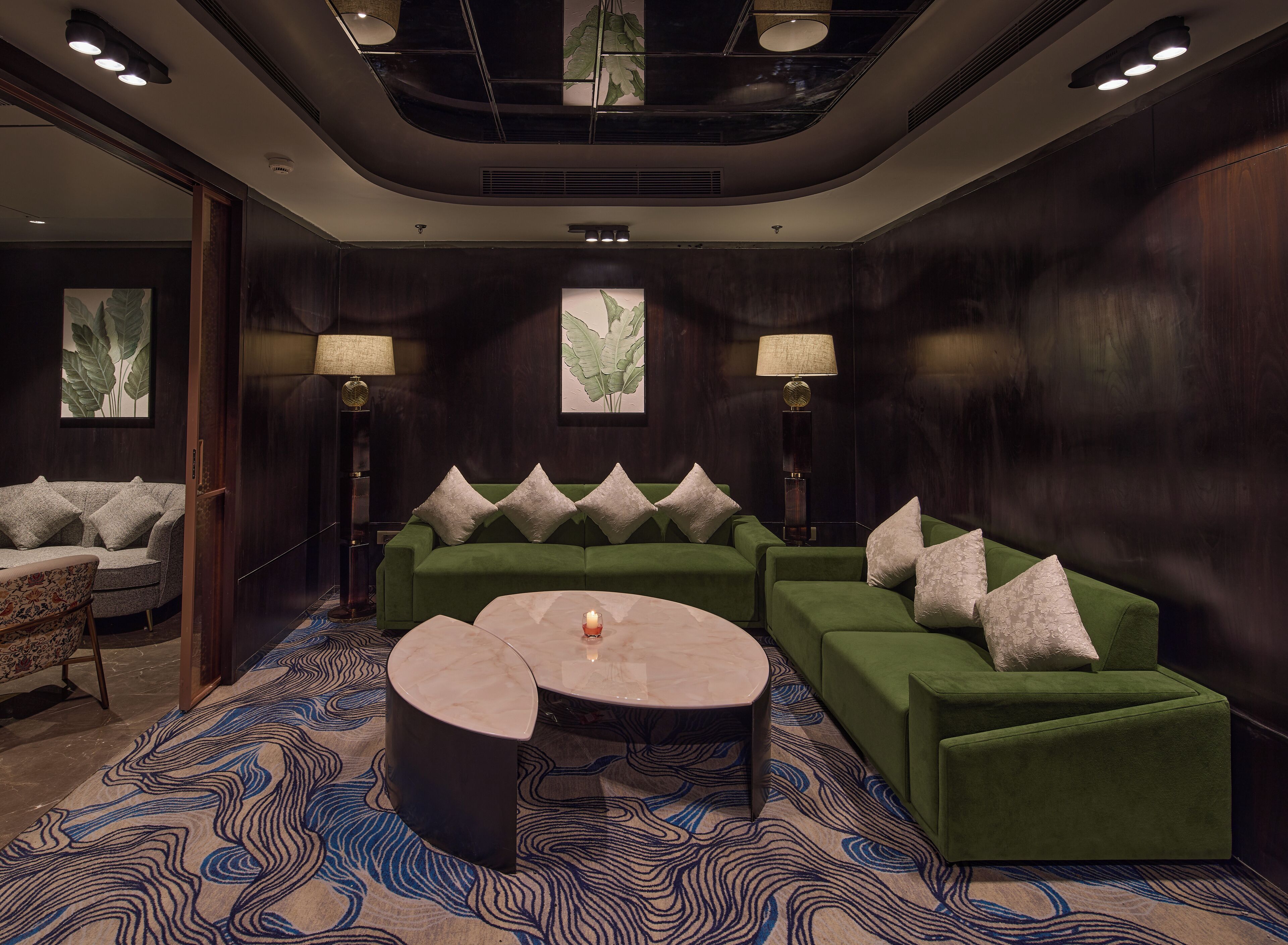 Una zona relax moderna con un divano verde, un tavolino rotondo e una moquette fantasia.