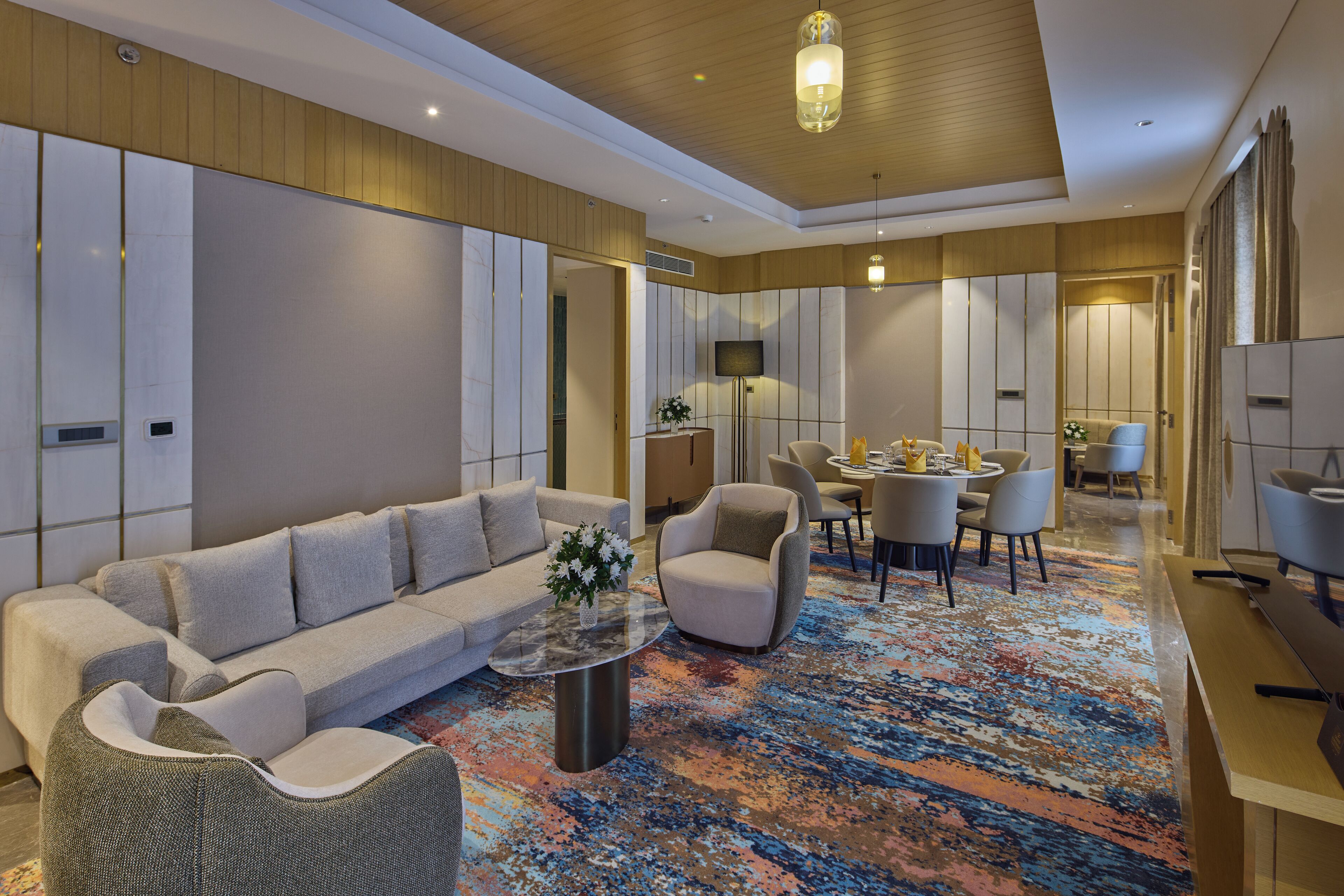 Un moderno vestíbulo de hotel con un sofá, sillones, una mesa de centro, una zona de comedor y un espejo grande.